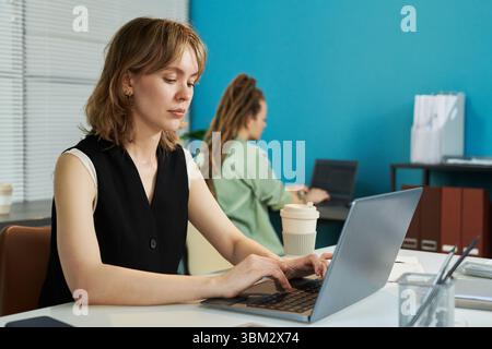 Young Adult Caucasian Woman Typing Neural Network Code in Shared Workspace Stock Photo