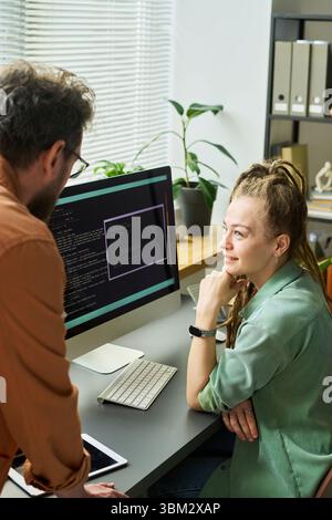 Young Caucasian Woman Collaborating with Colleague on Neural Network Coding Stock Photo