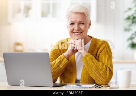 Happy elderly lady waiting for webinar, using laptop Stock Photo