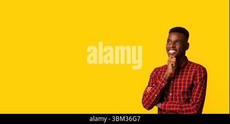 Portraif Of Pensive Dreamy African American Guy Standing Isolated On Yellow Background Stock Photo