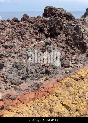 Layered texture of volcanic rocks, background with warm orange, yellow and gray stripes. Layers indicate ancient geological processes, creating a natu Stock Photo