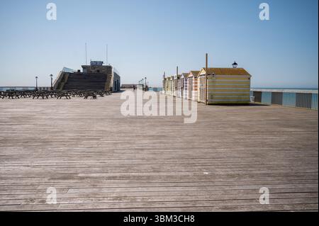 yellow and white striped beach huts on Hasstings pier Stock Photo