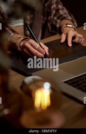 female hands with graphic tablet retouching photo on laptop computer at night Stock Photo
