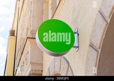 Round green signboard mockup on stone wall in bright daylight, perfect for branding, identity, logo or storefront promotion Stock Photo