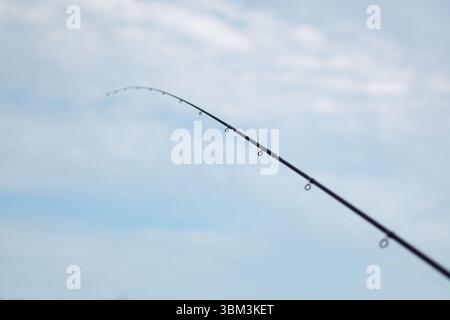 Fishing rod spinning with blurred background. Concept of fishing in river, pond, lake. Stock Photo
