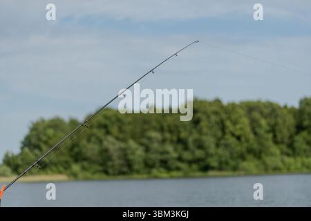Fishing rod spinning with line on blurred background. Concept of fishing in river, pond, lake. Stock Photo