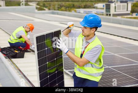Technician Installing And Maintaining Solar Panels On Roof For Renewable Power Stock Photo