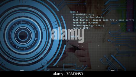 Holding smartphone with hands wearing long sleeves at desk showing CSS code over digital interface Stock Photo