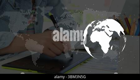 Holding stylus, artist drawing on tablet at desk, showing colored pencils and world map overlay Stock Photo