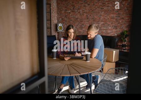 Couple discussing together at home over coffee in a cozy brick interior Stock Photo