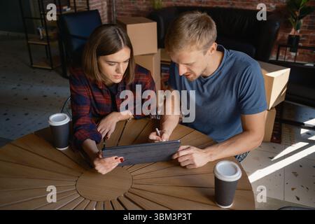Two people collaborating on a tablet while sitting inside a modern workspace Stock Photo