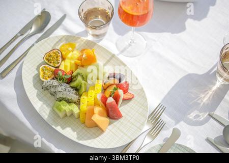 Luxury summer breakfast with colorful fruit salad on sunny table top at tropical resort hotel, closeup view of fresh healthy morning food in relaxing Stock Photo