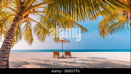 Fantastic summer panoramic beach landscape romantic couple chairs under umbrella palm trees luxury destination relax tropical vibes peaceful seaside Stock Photo