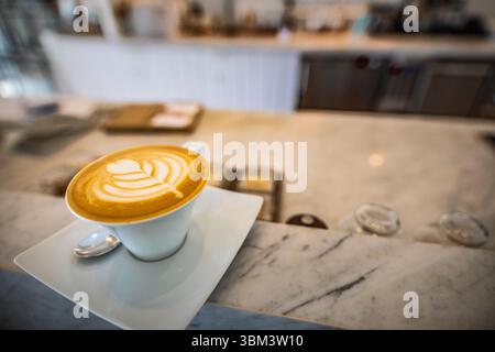Latte art on marble counter in elegant cafe with soft blurred background, stylish coffee shop interior scene for relaxation, modern beverage concept Stock Photo