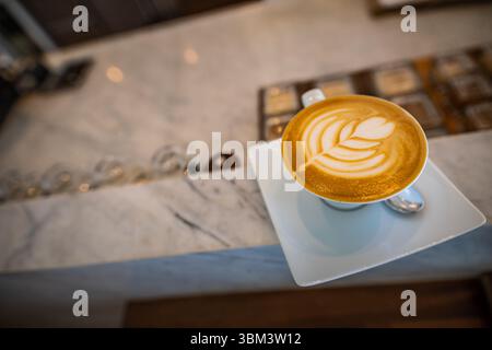 Latte art on marble counter in elegant cafe with soft blurred background, stylish coffee shop interior scene for relaxation, modern beverage concept Stock Photo