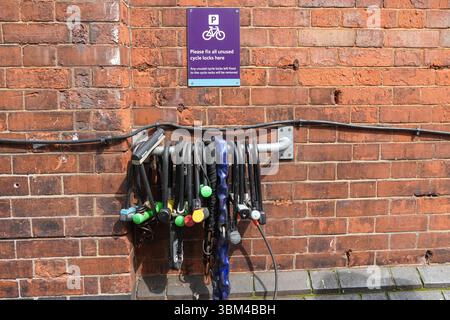 Bicycle locks, cycle locks  hanging fixed to the wall next to bicycle rack in London England United Kingdom UK Stock Photo