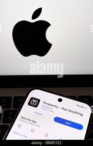 Perplexity AI open screen on smartphone positioned in front of Apple logo on computer. Stafford, United Kingdom, June 24, 2025 Stock Photo