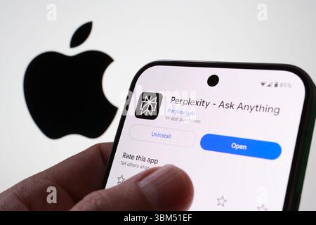 Perplexity AI interface held by user in front of Apple logo on illuminated background. Stafford, United Kingdom, June 24, 2025 Stock Photo