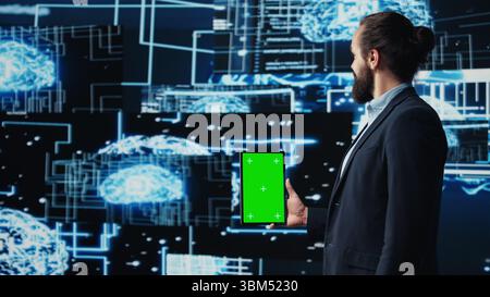 Studying neural networks systems, young IT specialist implements artificial intelligence with mockup screen on tablet. Man using automation for modern AI strategy and innovation. Camera B. Stock Photo