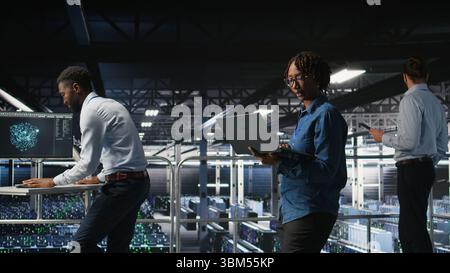 Data center software developers using devices to review AI LLM visualizations. IT professionals working together to analyze neural networks outputs, ensuring stable gear operations Stock Photo