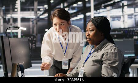 Cheerful data center technicians satisfied with results after collaborating on AI automation deployment. Happy server hub coworkers adjust machine learning configurations, working together, camera A Stock Photo