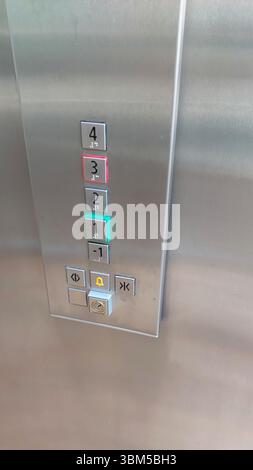 A remote control panel inside an elevator shows illuminated buttons for floors one to four. The active button is highlighted in green, indicating sele Stock Photo