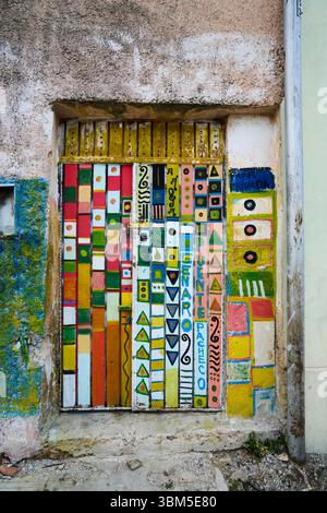 Mexico, Merida. Colorful hand-painted door with geometric patterns and text on a weathered wall, showcasing local artistic expression and culture. (Ed Stock Photo