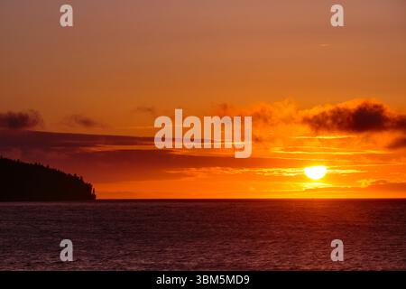 Sun setting on horizon over the Strait of Juan de Fuca, Port Angeles, Washington State, USA. Stock Photo