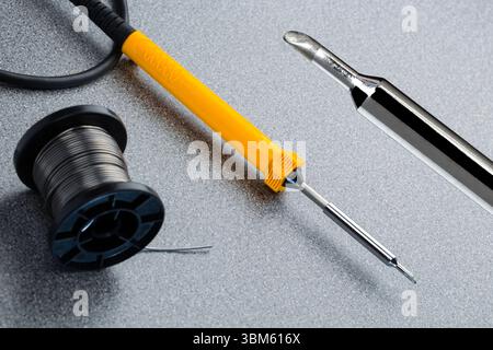 Electric soldering iron. A soldering iron is a tool used to melt an alloy of tin and lead, called solder, to join pieces of metal. This soldering iron is powered by electricity to heat the tip (also called the bit). It is mainly used in electronics assembly, joining wires or adding components to a circuit board. The heated tip (right) is applied to two or more metal parts to melt the solder. When the solder metal cools it forms a strong bond with good electrical transmission properties. Stock Photo