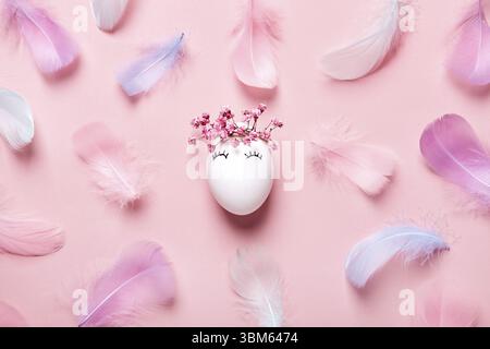 White Easter eggs with natural flowers wreath on soft pink feathers background. Zero Waste Easter Concept Stock Photo
