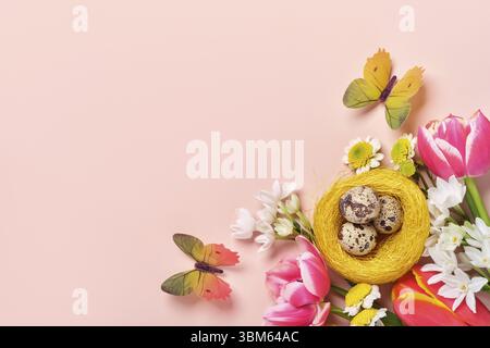Easter creative composition. Spring flowers, quail eggs in nest and butterflies on pink background. Easter greeting card Stock Photo