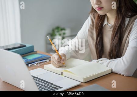 Asian woman using laptop to study student engaged in online learning at college Stock Photo