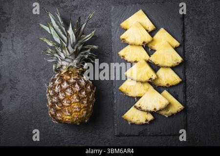 Ripe pineapple and slices on a black background Stock Photo