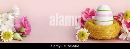 Easter creative composition. Spring flowers, Easter egg and butterflies on pink banner. Easter card Stock Photo