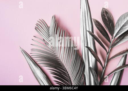 Painted in silver tropical leaves on pink pastel background. Natural Creative layout. Minimal surrealism background Stock Photo