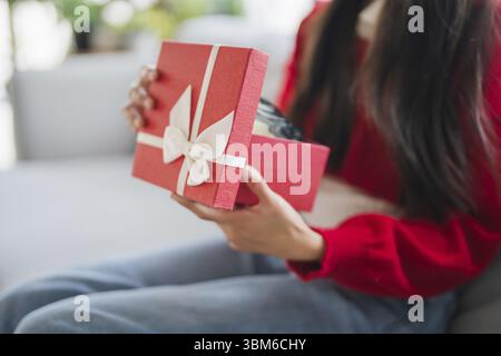Receiving Valentine present. Cheerful girl asian holding gift box Stock Photo