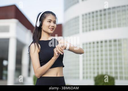 Sporty asian woman checking pulse in smart watch in sportswear workout with health app on smart watch After Exercise wellness health sportswoman Stock Photo