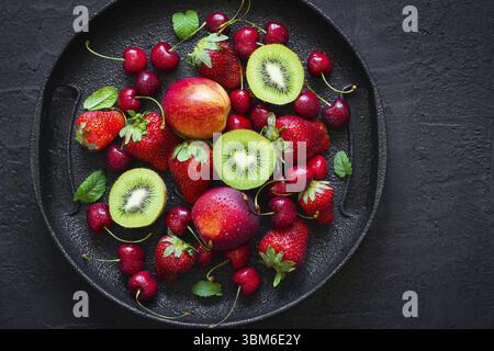 Mix of summer berries and fruits on a black plate. Top view with copy space Stock Photo