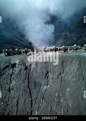 Tourists on the rim of Mt Bromo Volcano (Gunung Bromo) East Java, Indonesia - aerial Stock Photo