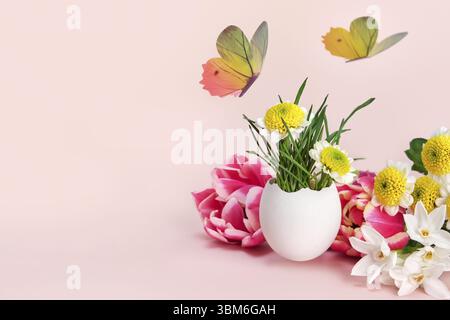 Easter creative composition. Spring flowers, Easter egg and butterflies on a pink background. Easter card Stock Photo