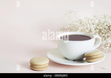Coffee cup, macaroon and gypsophila flowers on pink background Stock Photo