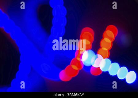 Red and blue neon blurry curls of bokeh lights on black. Abstract background of 80s colors Stock Photo