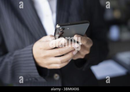 Asian Business woman using smart phone spending time checking news social media Stock Photo