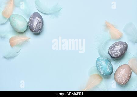 Happy easter greeting card template. Easter eggs and feathers on a blue pastel background. Flat lay, copy space Stock Photo