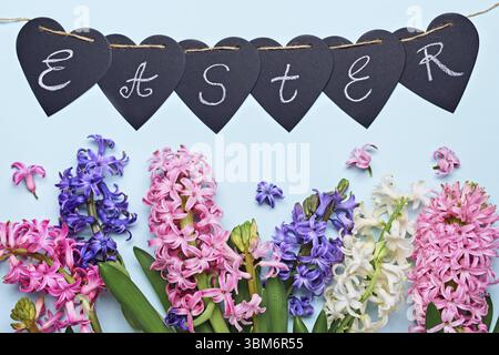 Happy easter greeting card. Multicolored hyacinth flowers and garland with Easter word. Easter concept. Flat lay Stock Photo