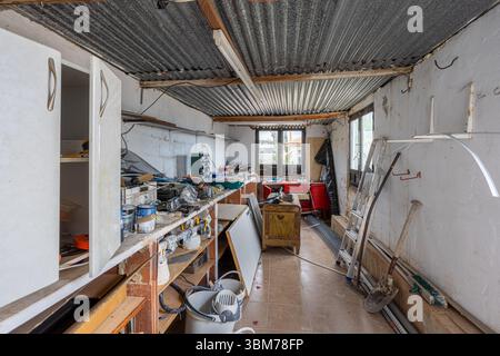 Interior of a cluttered workshop showing tools, workbenches, storage, and construction materials. Stock Photo