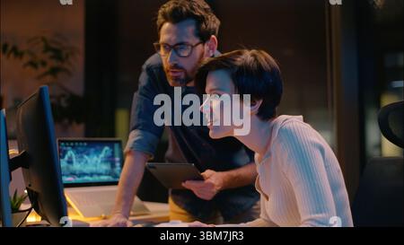 Business man woman cooperation in night office trader broker working computer stock market analysis bitcoin trading online crypto currency businessman Stock Photo