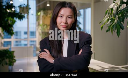 Successful businesswoman Asian business woman Korean girl entrepreneur in office posing with crossed hands confident employer leader indoors Japanese Stock Photo