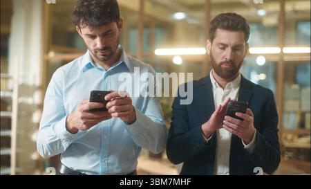 Busy men colleagues businessmen business partners Caucasian guys co-workers managers entrepreneurs usage mobile phones gadgets addict male employees Stock Photo