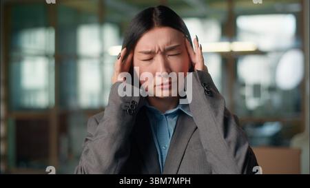 Asian business woman businesswoman feel headache tired exhausted Chinese Japanese girl Korean female employee manager overworked in office massaging Stock Photo